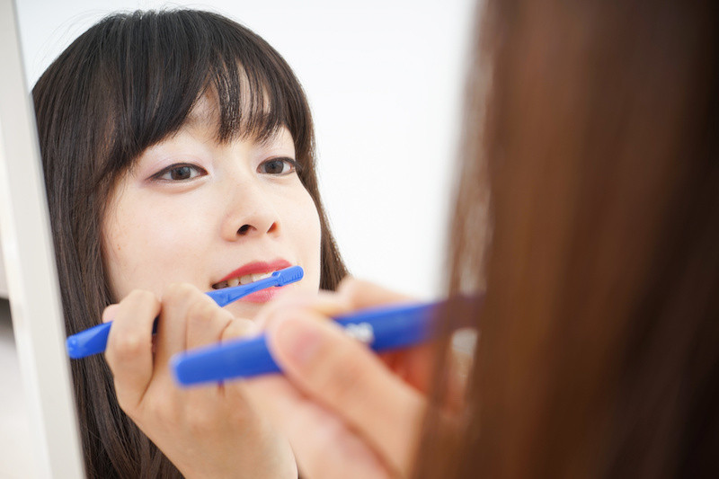 鏡を見て歯を磨く女性